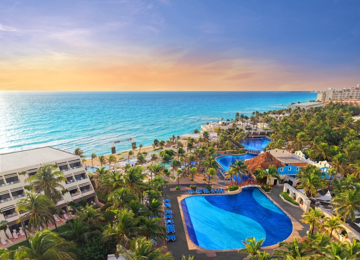 Panoramic view of the pools and beach at The Pyramid Cancun hotel at sunset