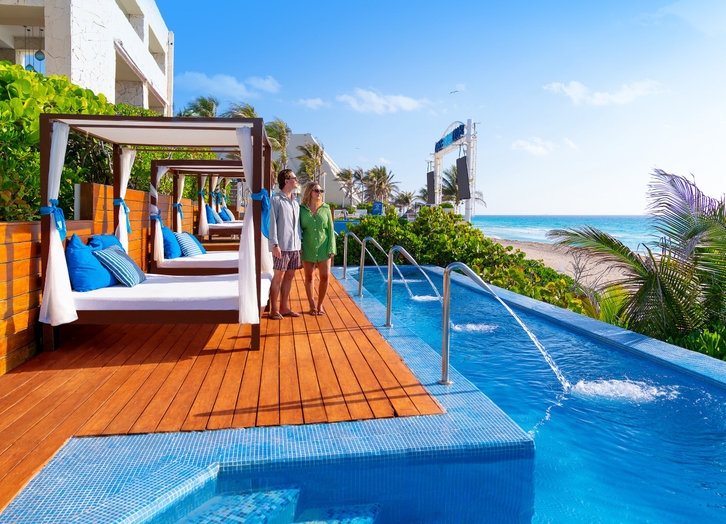 Couple beside the Balinese daybeds and pool overlooking the sea at The Pyramid Cancun